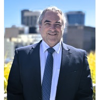 Man wearing a blue suit with striped tie smiling at the camera