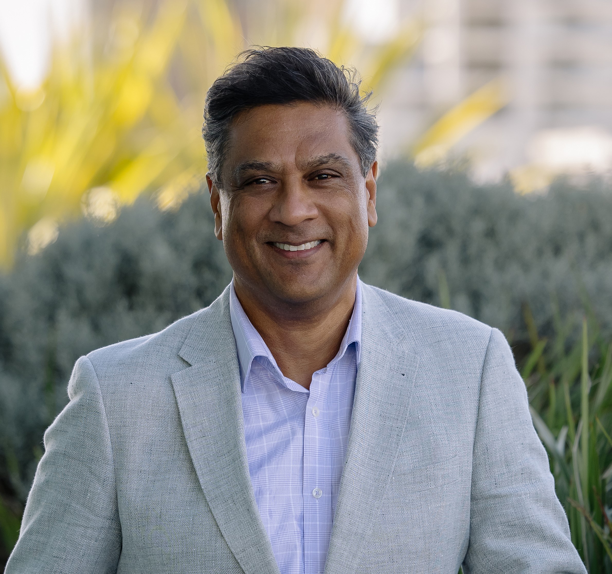 Man wearing a blue and white suit smiling at the camera